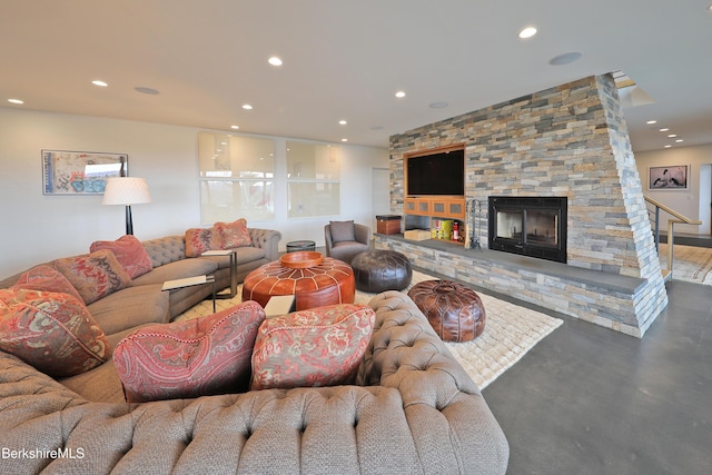 living area featuring finished concrete floors, recessed lighting, and a stone fireplace