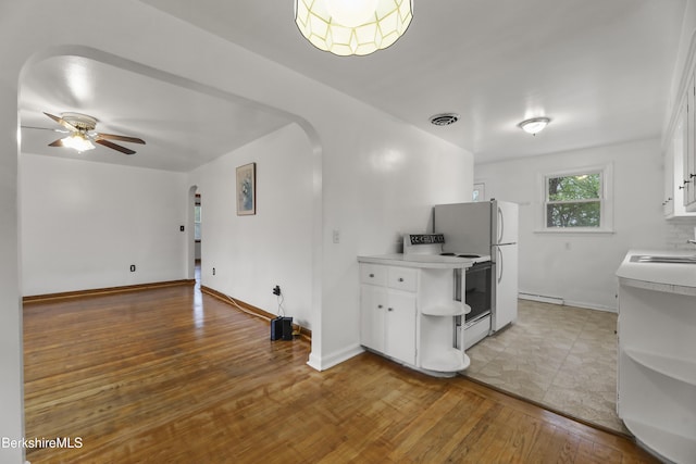 kitchen with arched walkways, light countertops, ceiling fan, white cabinets, and light wood-style flooring