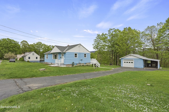 view of front of home featuring a detached garage, an outdoor structure, a front yard, and driveway