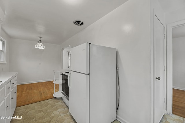 kitchen with freestanding refrigerator, light countertops, range with electric stovetop, white cabinetry, and baseboards