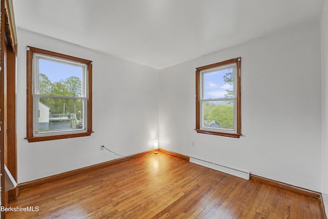 unfurnished room with a baseboard radiator, wood-type flooring, and baseboards