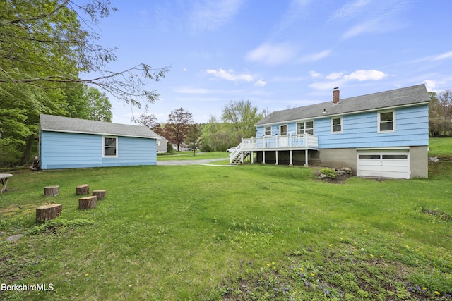 rear view of property with stairway, an attached garage, a yard, and a chimney