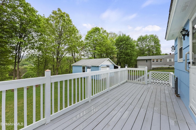 wooden deck featuring a yard, an outdoor structure, and view of wooded area
