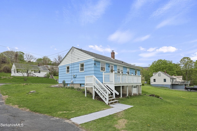 view of front of property with a chimney, a front lawn, stairway, and a deck