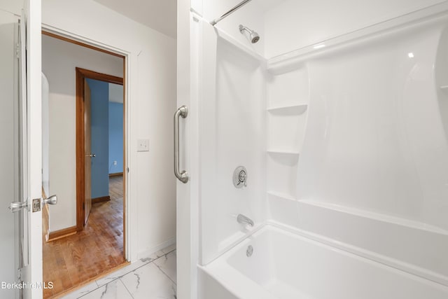 bathroom featuring marble look tiles, baseboards, and shower / washtub combination