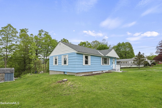 view of home's exterior with a lawn, an outbuilding, a shed, and roof with shingles