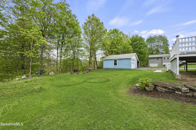 view of green lawn featuring an outdoor structure, a wooden deck, and a garage