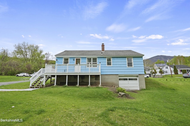 rear view of property featuring a deck, stairway, an attached garage, a chimney, and a yard