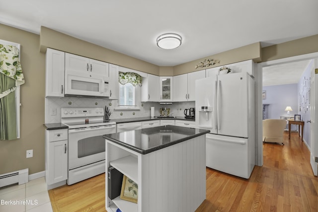 kitchen featuring tasteful backsplash, a baseboard radiator, dark countertops, white cabinets, and white appliances