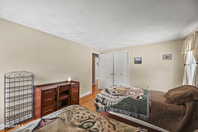 bedroom featuring light wood-style floors, baseboards, and a closet