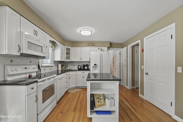 kitchen with white appliances, white cabinets, dark countertops, open shelves, and a sink