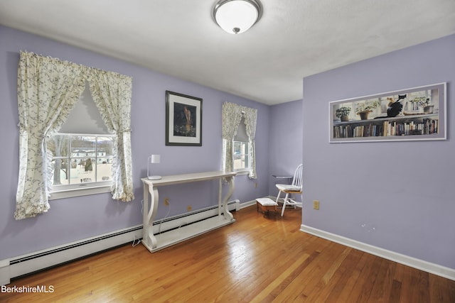 interior space featuring baseboards, hardwood / wood-style floors, baseboard heating, and a healthy amount of sunlight