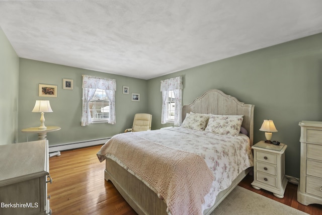 bedroom with baseboard heating and wood finished floors