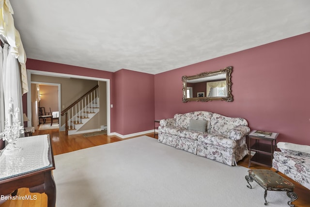 living room featuring stairway, a baseboard radiator, wood finished floors, and baseboards