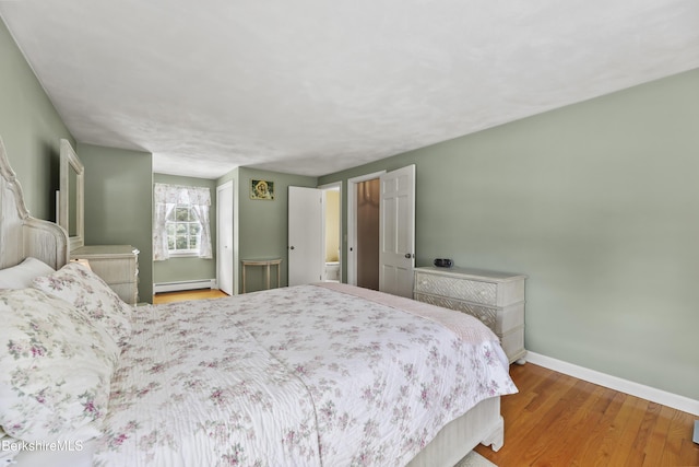 bedroom with baseboards, baseboard heating, and wood finished floors