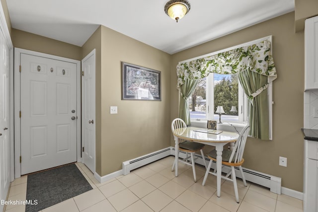 dining area featuring a baseboard radiator, light tile patterned flooring, and baseboards