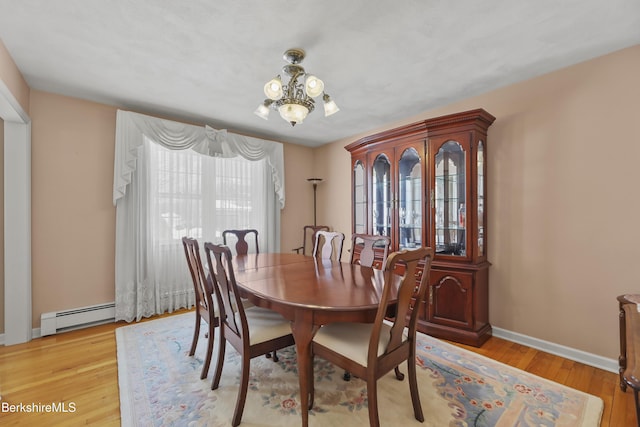 dining area with baseboards, a notable chandelier, baseboard heating, and wood finished floors