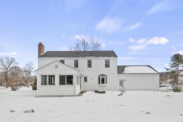 snow covered back of property with a chimney