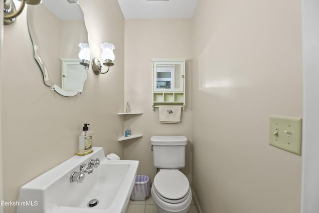 half bathroom featuring baseboards, a sink, toilet, and tile patterned floors