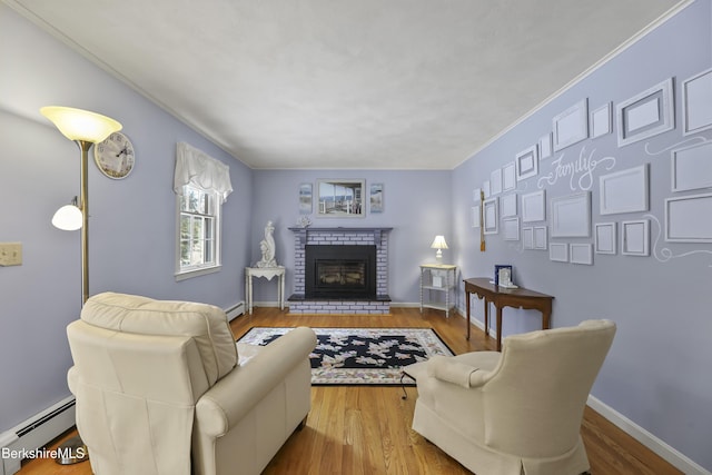 living area featuring baseboards, a baseboard radiator, wood finished floors, and a brick fireplace