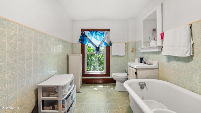 14 Hall St, North Adams, MA 01247 - full bathroom featuring a soaking tub, tile walls, toilet, vanity, and a wainscoted wall