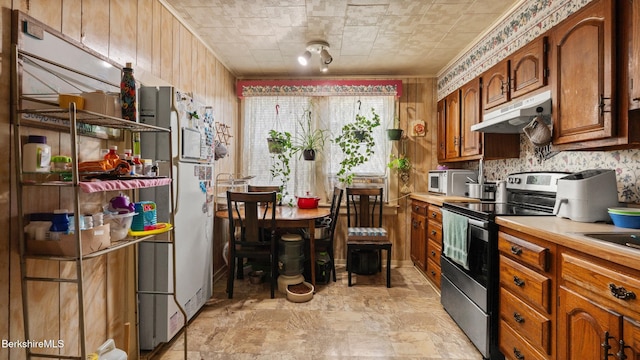 14 Hall St, North Adams, MA 01247 - kitchen with stainless steel electric range, under cabinet range hood, light countertops, brown cabinetry, and freestanding refrigerator