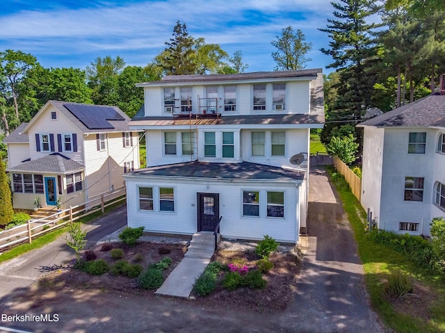 view of front of home with asphalt driveway and a balcony