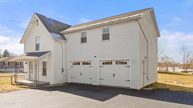 view of side of property featuring a garage and asphalt driveway