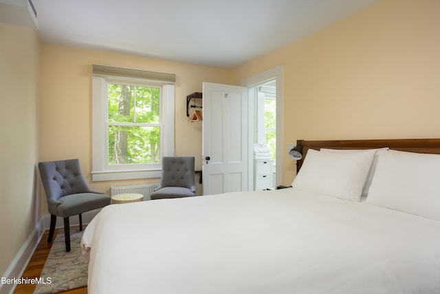 bedroom featuring radiator heating unit, baseboards, and wood finished floors