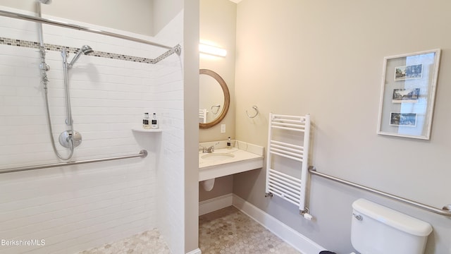 full bath with tiled shower, radiator heating unit, a sink, and toilet