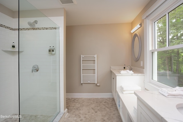 bathroom with radiator heating unit, baseboards, a tile shower, and vanity