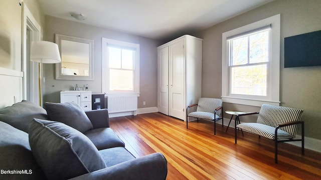 sitting room with baseboards, radiator heating unit, and light wood-style floors