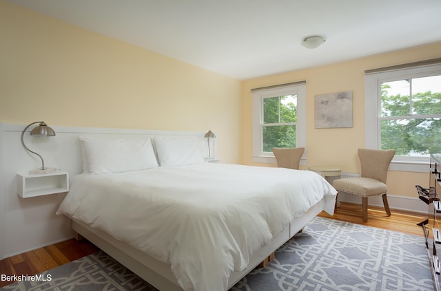 bedroom with multiple windows and wood finished floors