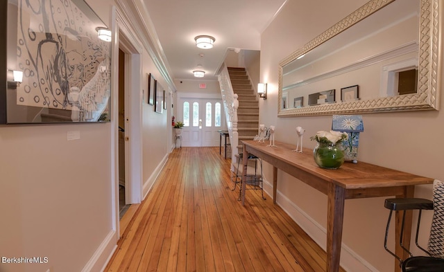 corridor featuring stairs, light wood-type flooring, and baseboards