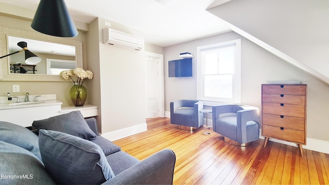 sitting room with lofted ceiling, a wall mounted air conditioner, hardwood / wood-style flooring, and baseboards