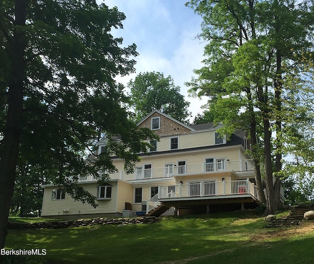 back of house with a lawn, a balcony, and a wooden deck