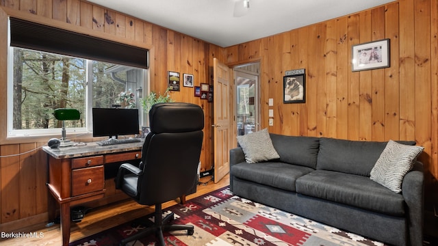 office space featuring wooden walls, a ceiling fan, and wood finished floors