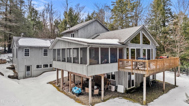 rear view of property with a shingled roof, a deck, and a sunroom