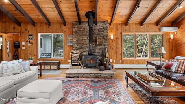 living area featuring a baseboard radiator, wooden walls, a wood stove, and a wall unit AC