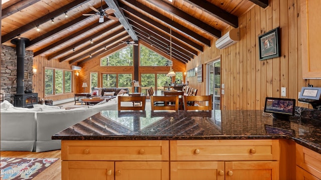 kitchen with wooden walls, ceiling fan, open floor plan, a peninsula, and a wood stove