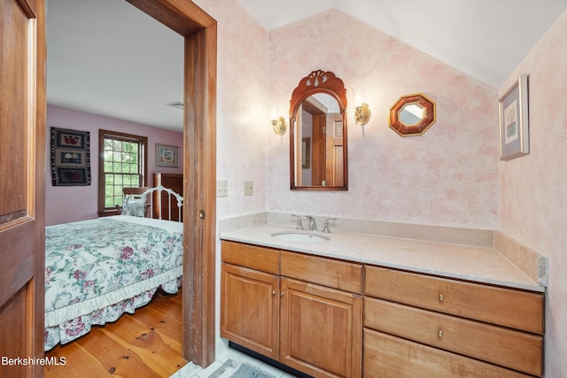 bathroom with vanity, wood-type flooring, and lofted ceiling