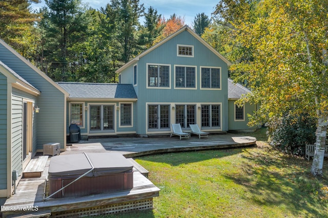 rear view of property featuring a hot tub, a lawn, and a wooden deck