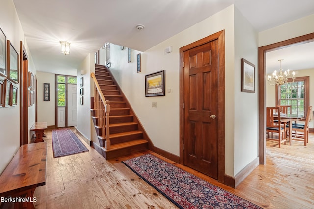 foyer entrance featuring plenty of natural light, light hardwood / wood-style floors, floor to ceiling windows, and an inviting chandelier