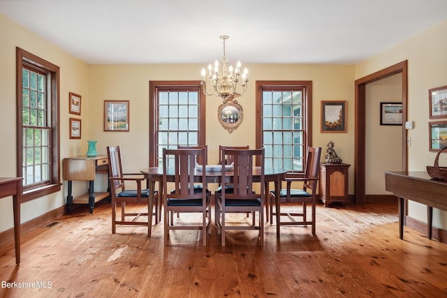 dining area with light hardwood / wood-style floors and an inviting chandelier