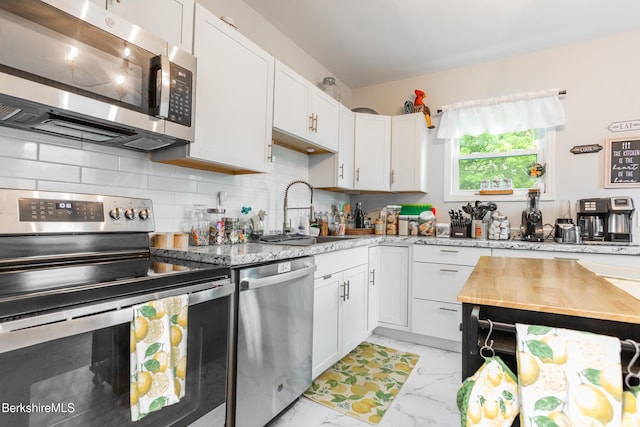 24 Front St Unit 22-24, Williamstown, MA 01267 - kitchen with appliances with stainless steel finishes, a sink, light marble finish floors, white cabinetry, and decorative backsplash