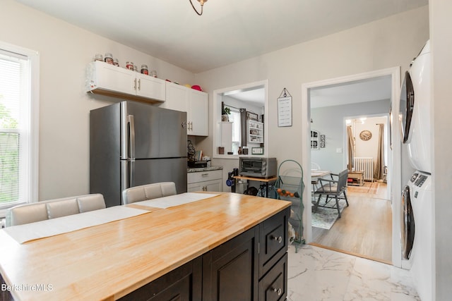 24 Front St Unit 22-24, Williamstown, MA 01267 - kitchen with freestanding refrigerator, estacked washer and dryer, wood counters, white cabinetry, and light marble finish flooring