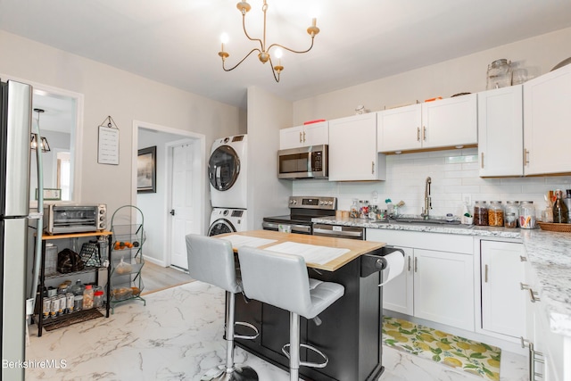24 Front St Unit 22-24, Williamstown, MA 01267 - kitchen featuring appliances with stainless steel finishes, estacked washer and dryer, backsplash, and a sink