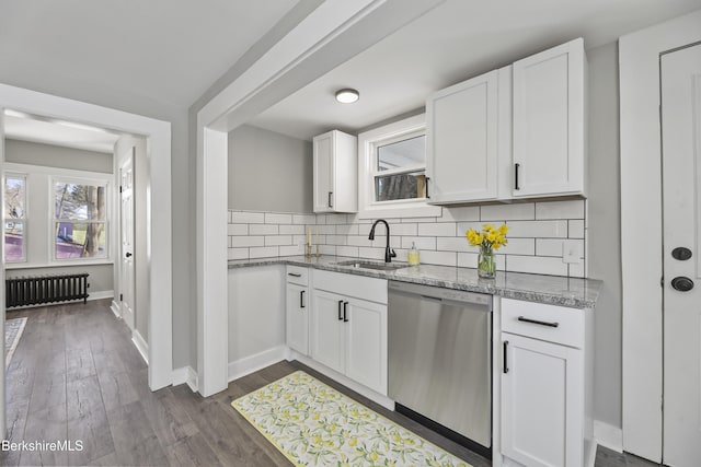 kitchen with radiator, decorative backsplash, stainless steel dishwasher, white cabinets, and a sink