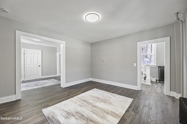 unfurnished room featuring radiator, dark wood-type flooring, and baseboards