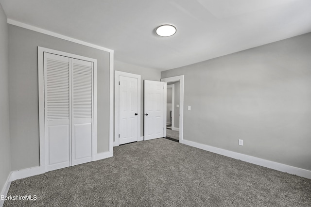 unfurnished bedroom featuring baseboards and dark colored carpet